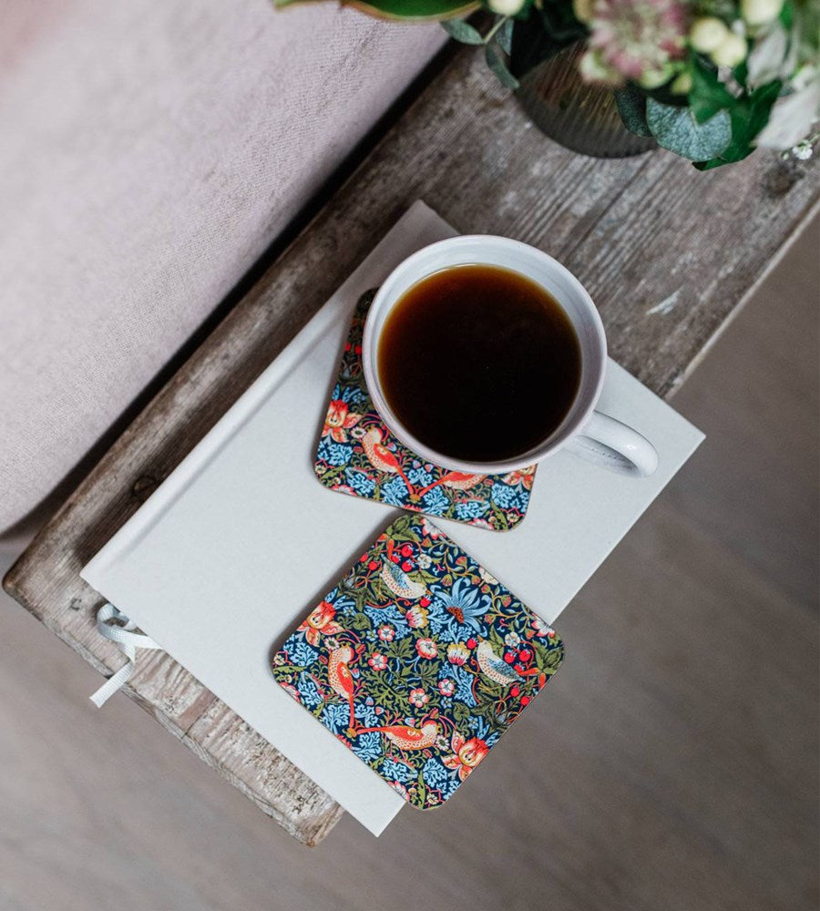 Cup of coffee on a tray with floral coasters on a wooden surface