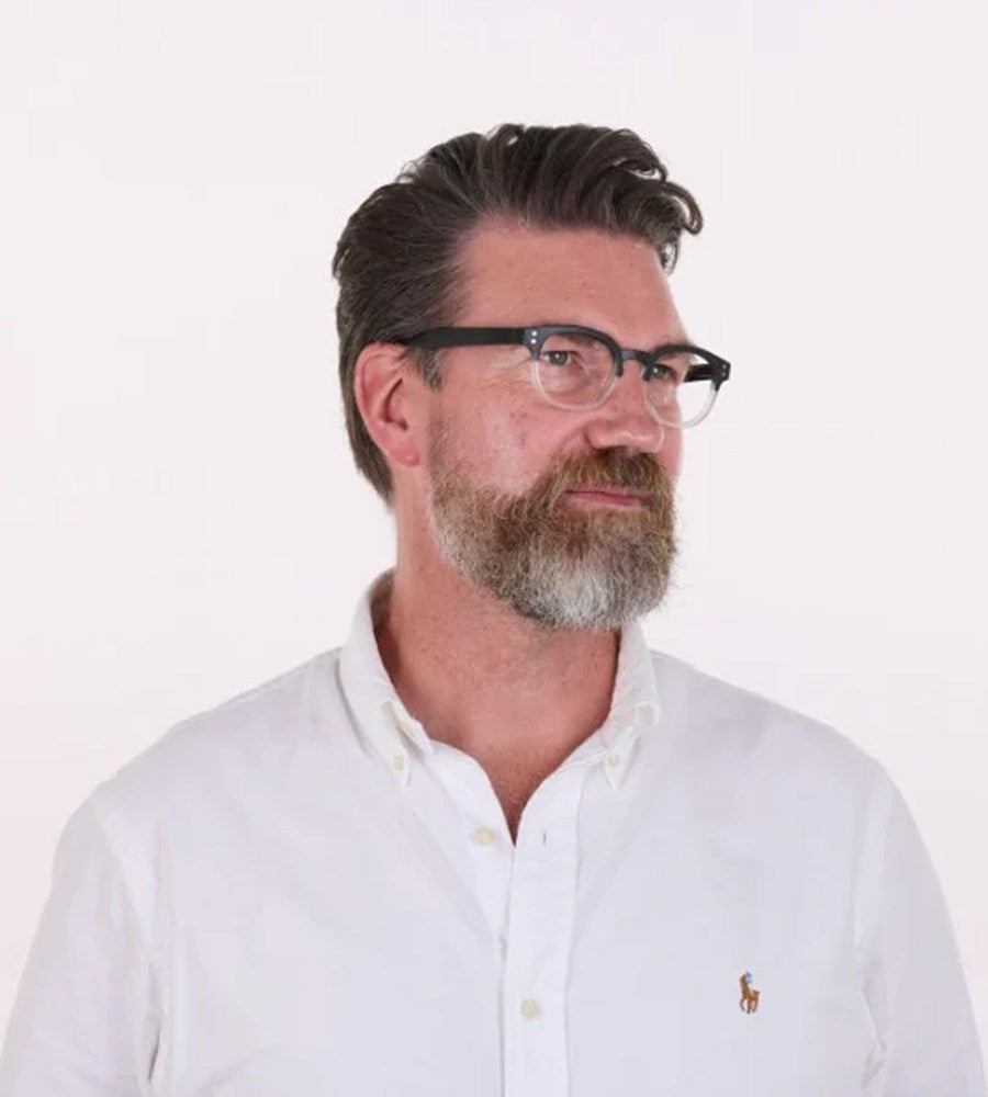 Man wearing glasses and a white shirt with a logo on a white background