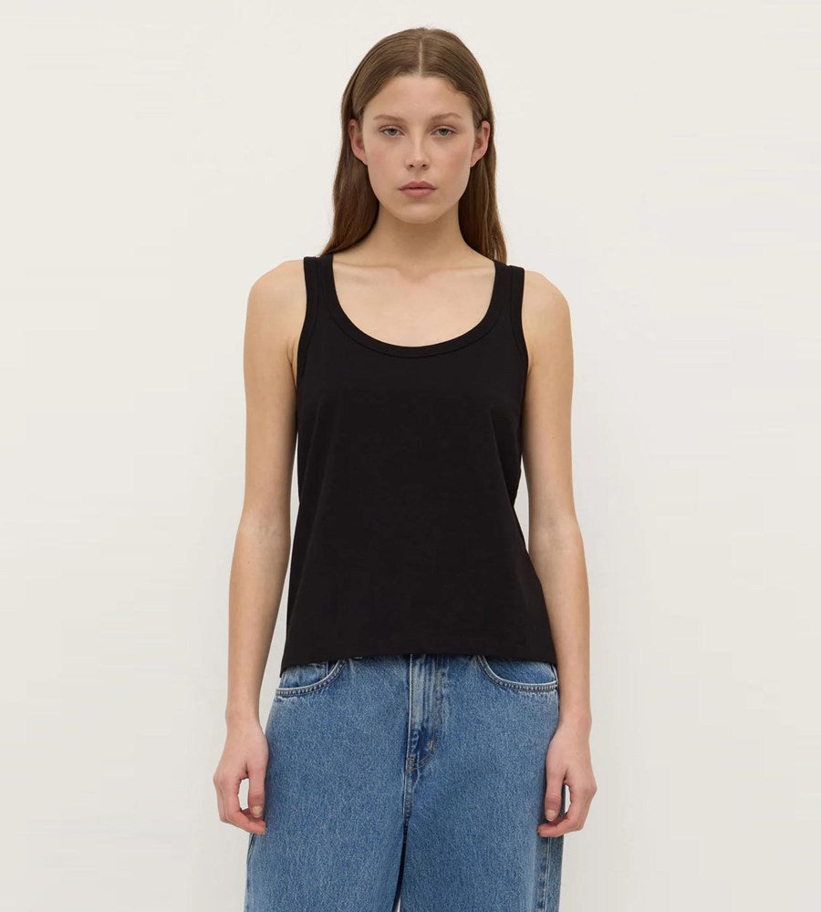 Woman wearing a black tank top and blue jeans on a white background