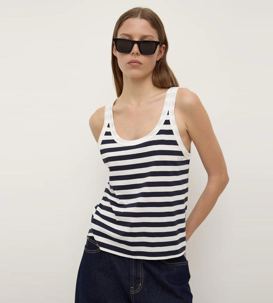 Woman wearing a navy and white striped tank top against a plain background