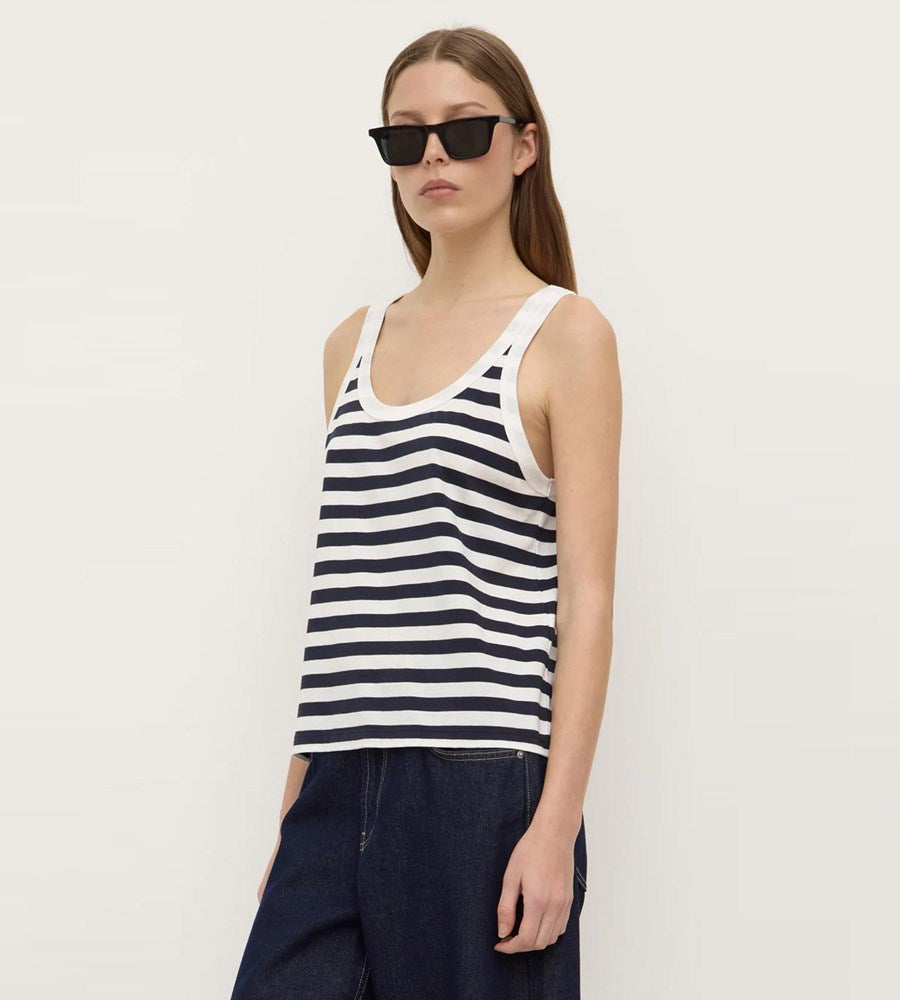 Woman wearing a striped tank top and sunglasses against a plain background