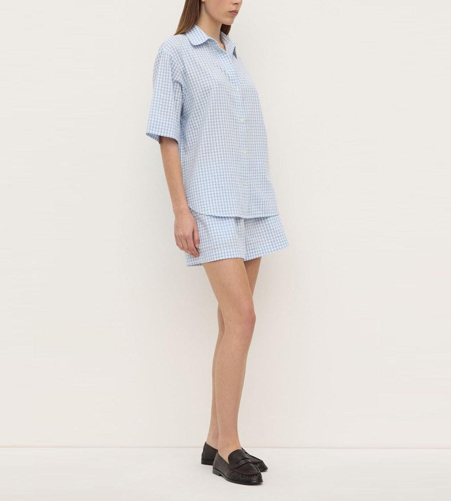 Person wearing a light blue checkered outfit on a white background