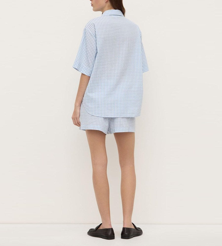 Person wearing a light blue checkered outfit on a white background