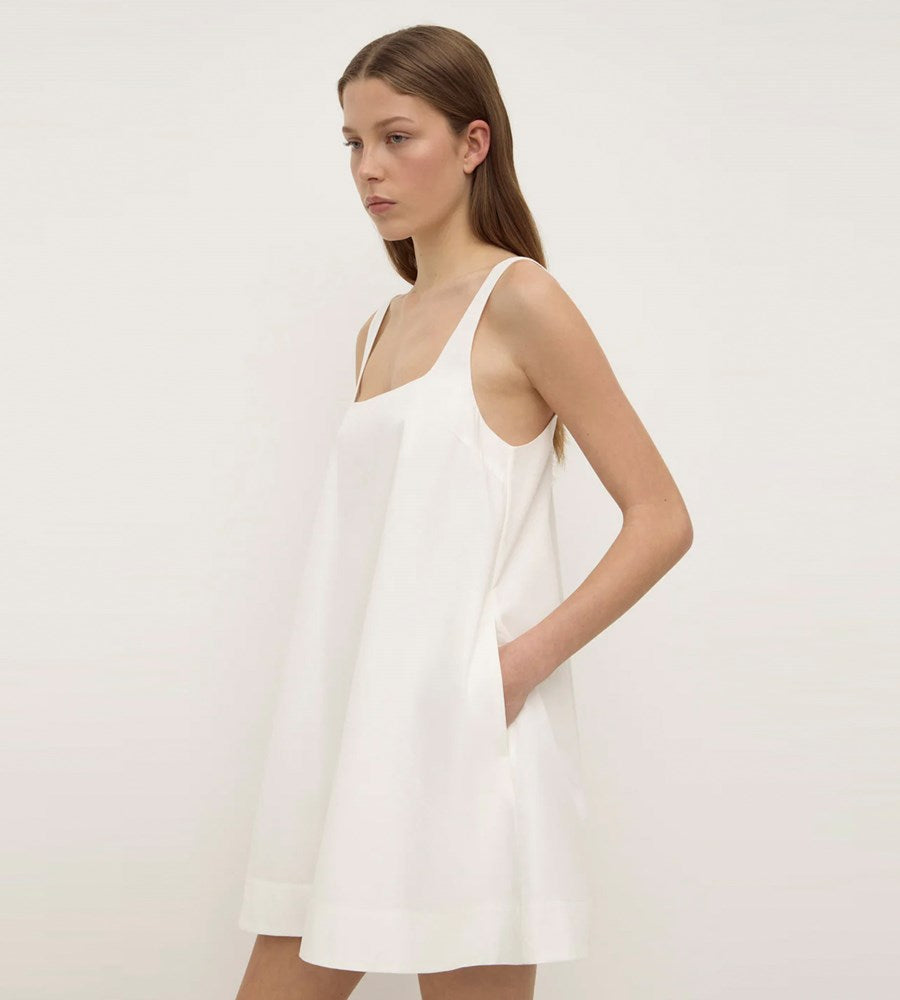 Woman wearing a white dress against a plain background