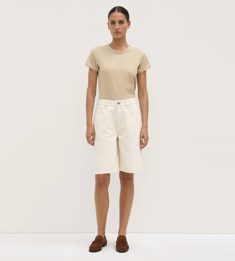 Person wearing a beige t-shirt and white shorts on a plain background