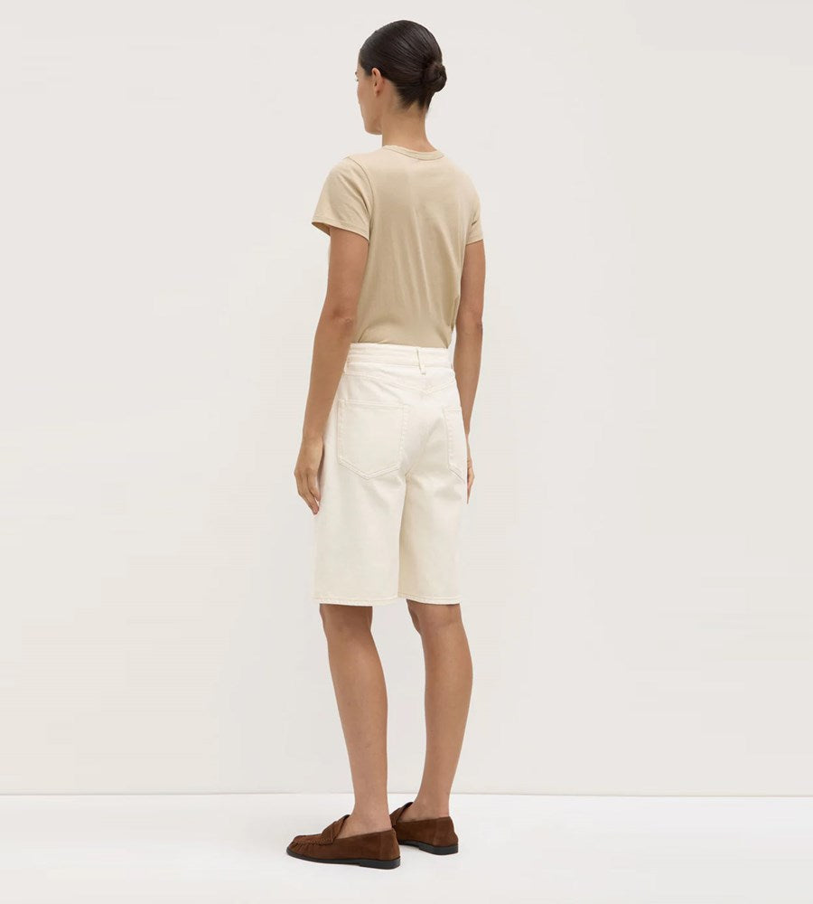 Person wearing a beige t-shirt and white skirt on a plain background