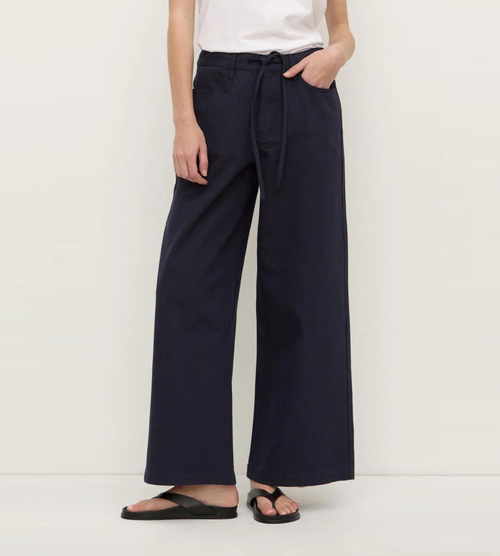 Person wearing navy wide-leg pants on a white background
