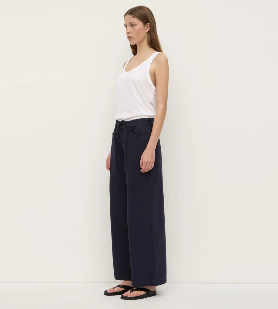 Woman wearing a white top and navy wide-leg pants against a white background