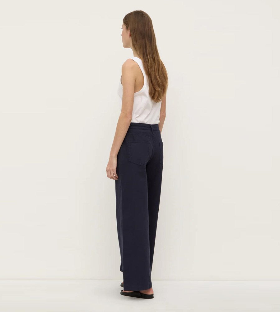Woman wearing navy pants and a white top on a white background