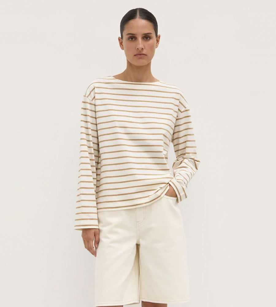 Person wearing a striped long-sleeve shirt and white pants on a plain background