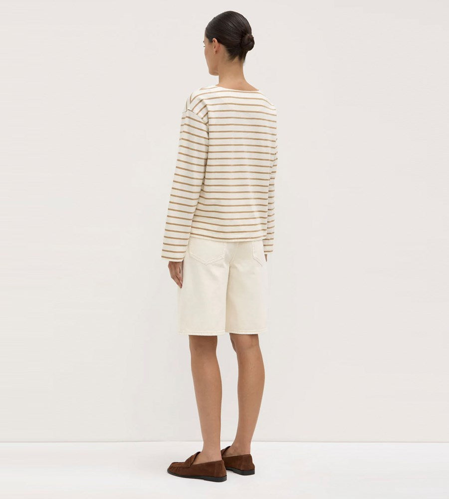 Person wearing a striped shirt and white shorts on a plain background