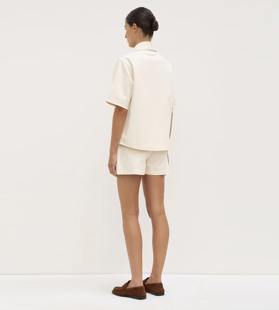 Person wearing a white outfit with shorts on a plain background