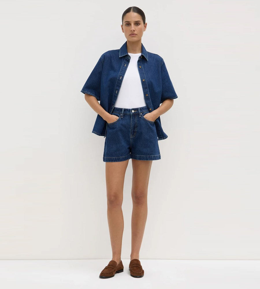 Person wearing a denim jacket and shorts with a white background