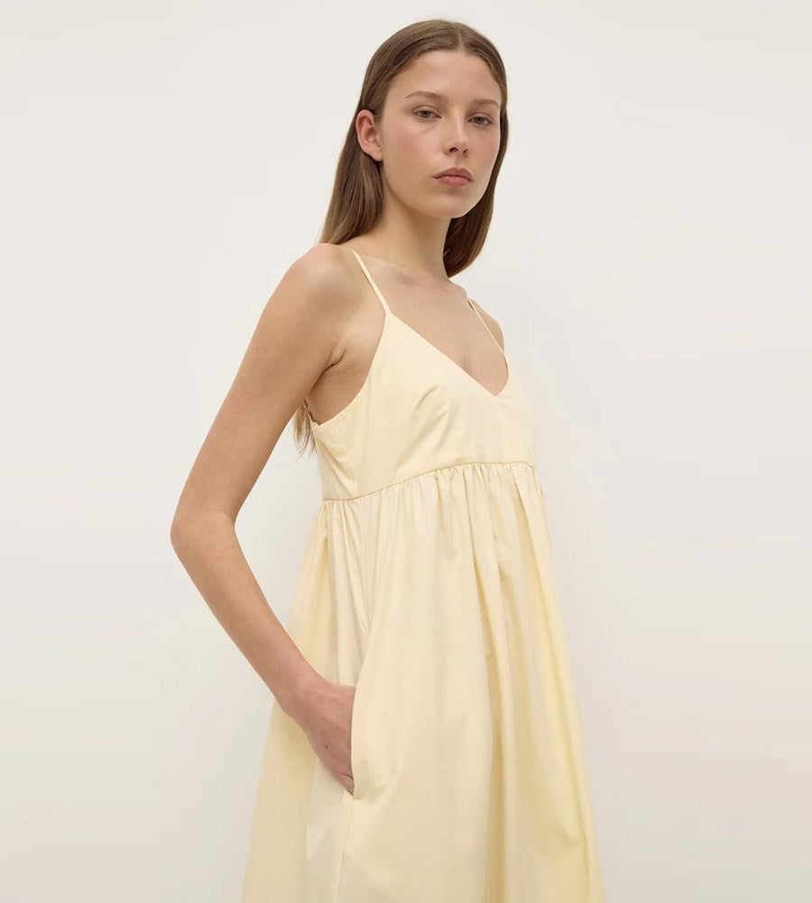 Woman wearing a light yellow dress against a white background