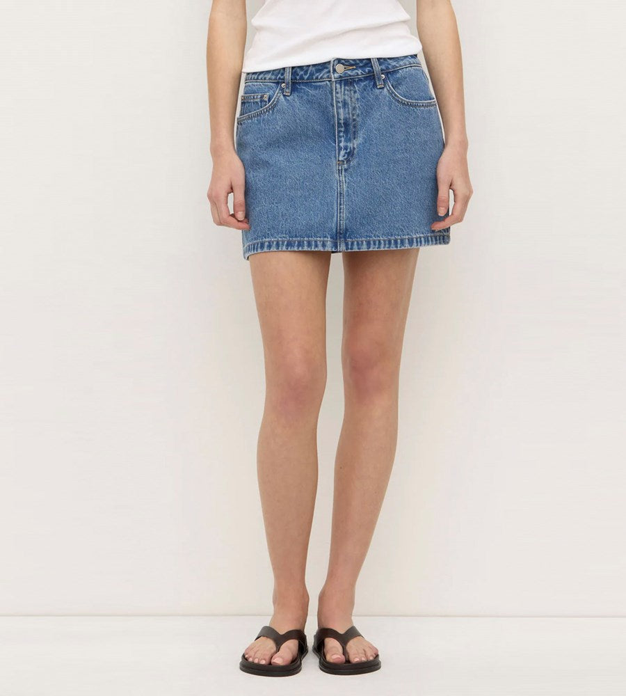 Person wearing a blue denim skirt on a white background