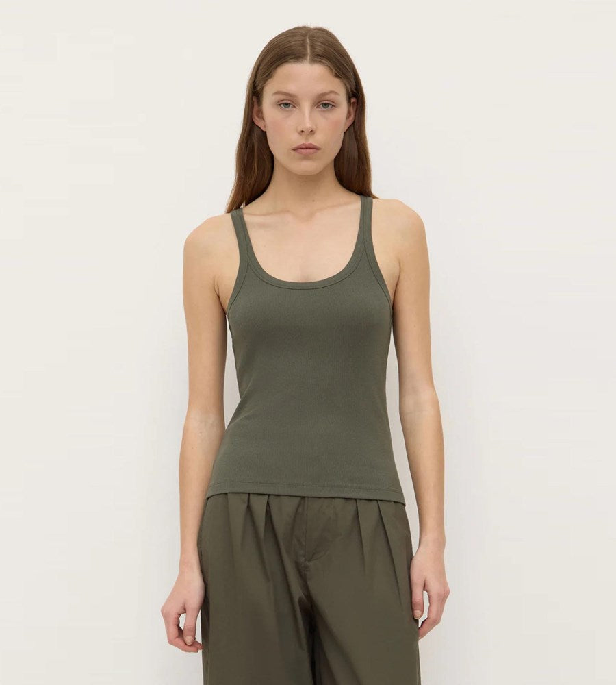 Woman wearing a green tank top and pants on a plain background