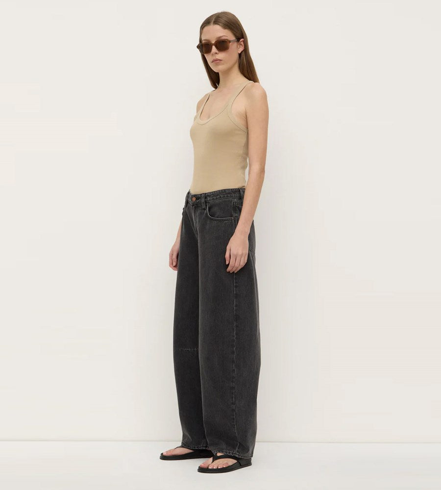 Woman wearing a beige top and black wide-leg jeans against a white background