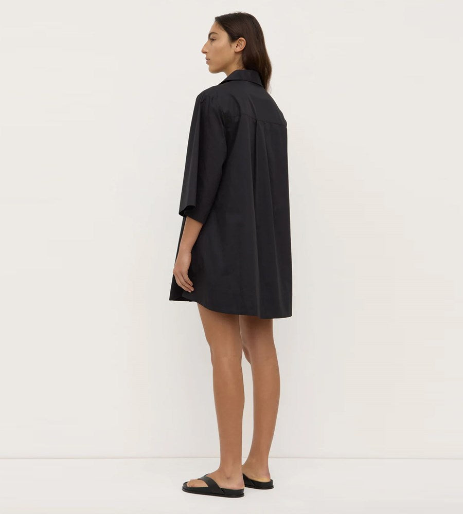 Woman wearing a black shirt dress against a white background