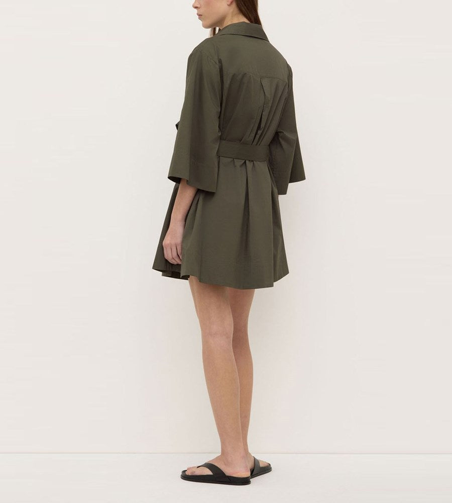 Person wearing a green dress with a belt on a white background
