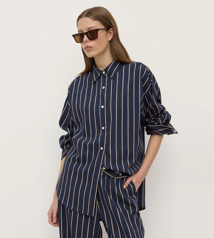 Person wearing a navy striped shirt and pants with sunglasses on a white background