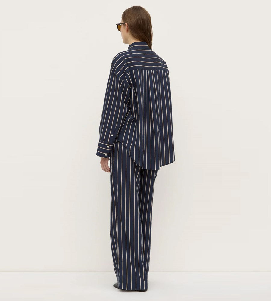 Person wearing a navy striped pajama set on a white background