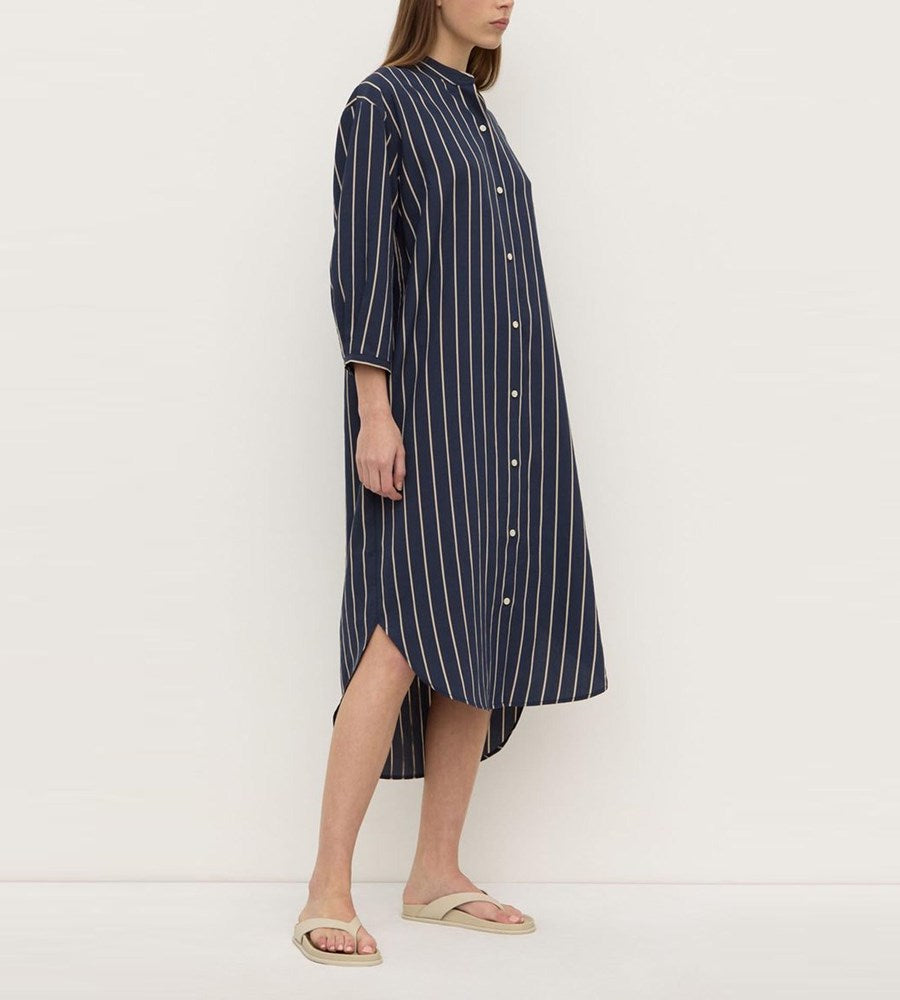Woman wearing a navy striped dress on a white background