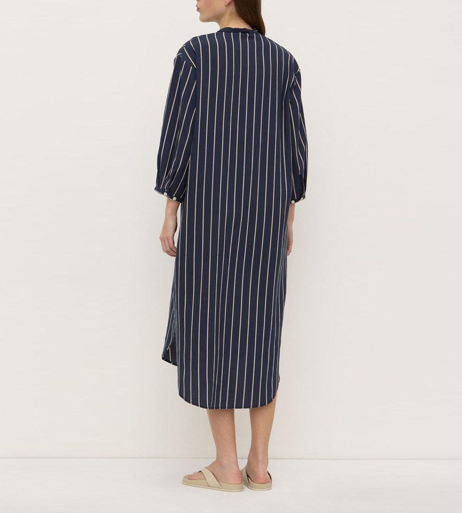 Woman wearing a navy and white striped dress on a white background