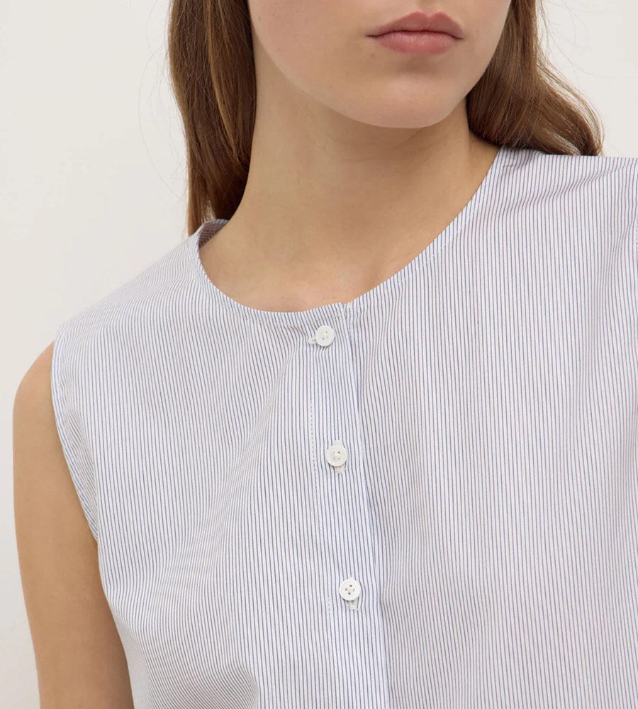 Close-up of a person wearing a sleeveless white and blue striped shirt against a plain background