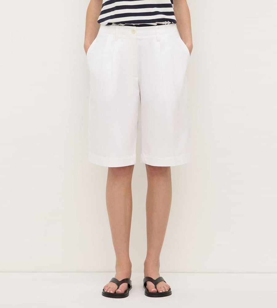 Person wearing a white skirt and striped top on a plain background