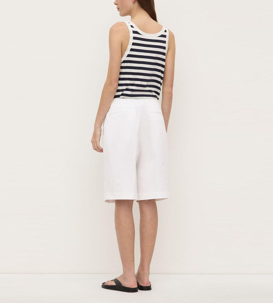 Person wearing a black and white striped tank top and white shorts on a plain background