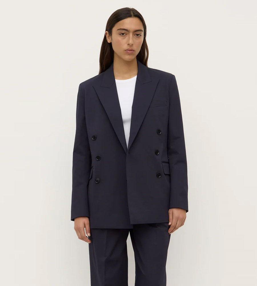 Person wearing a navy double-breasted blazer and pants on a white background