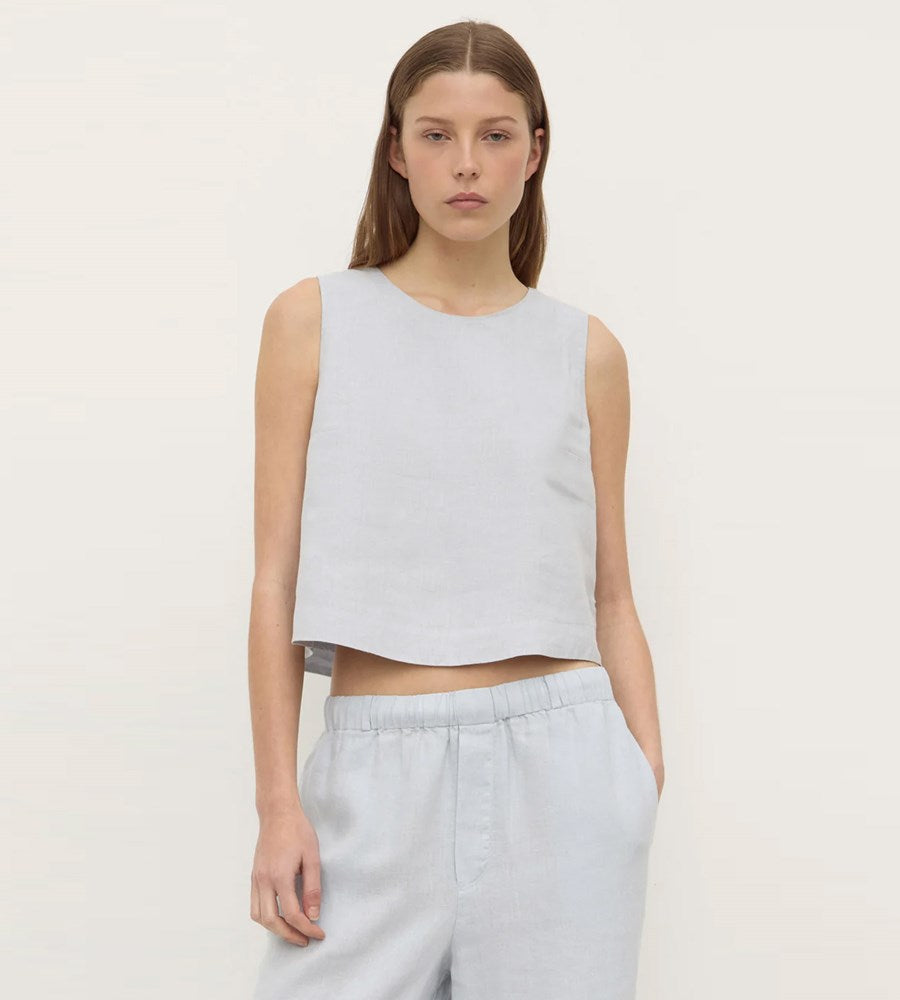 Woman wearing a light gray sleeveless top and pants on a white background