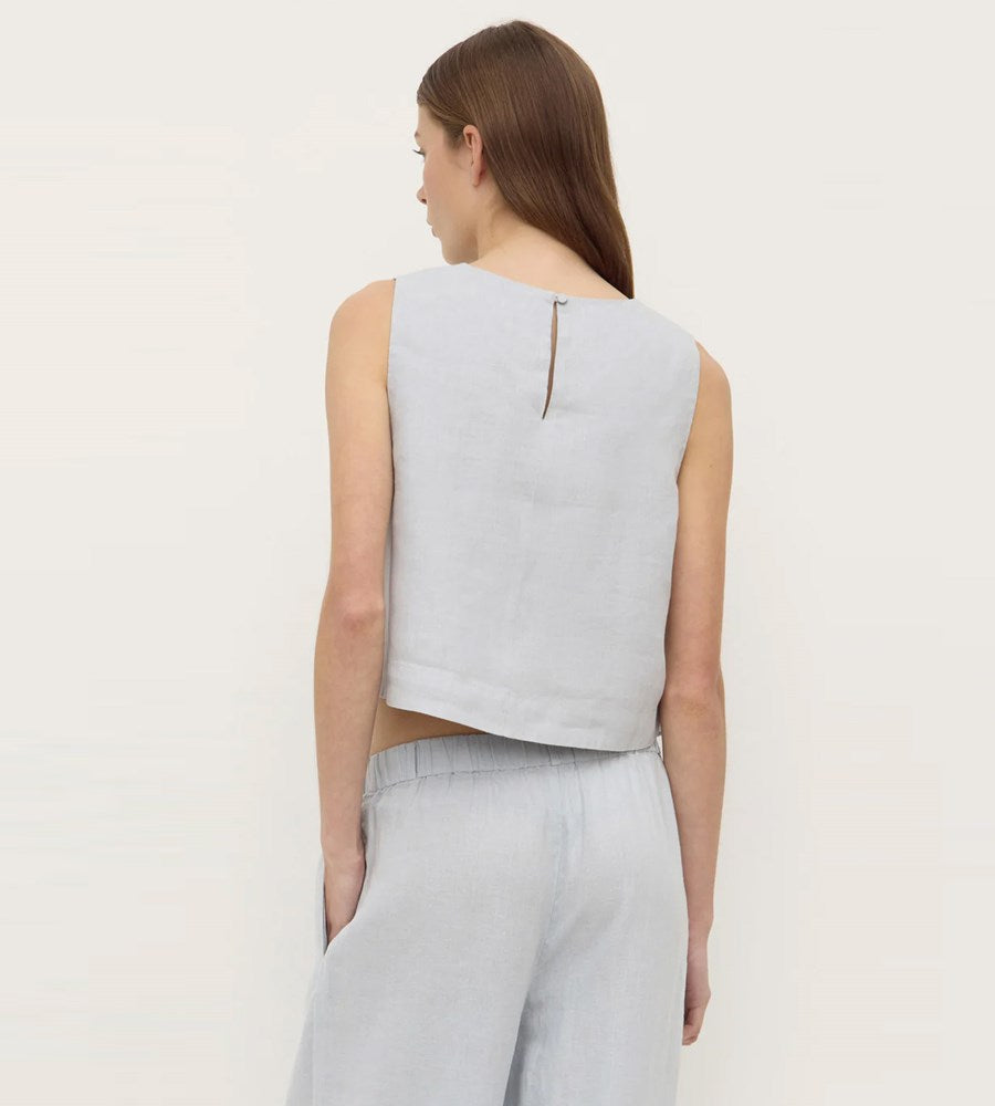Woman wearing a light gray sleeveless top and pants on a white background