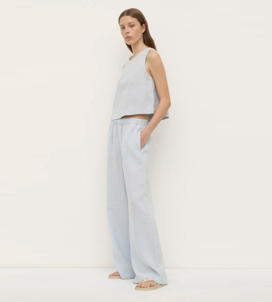 Woman wearing a light gray sleeveless top and wide-leg pants on a white background