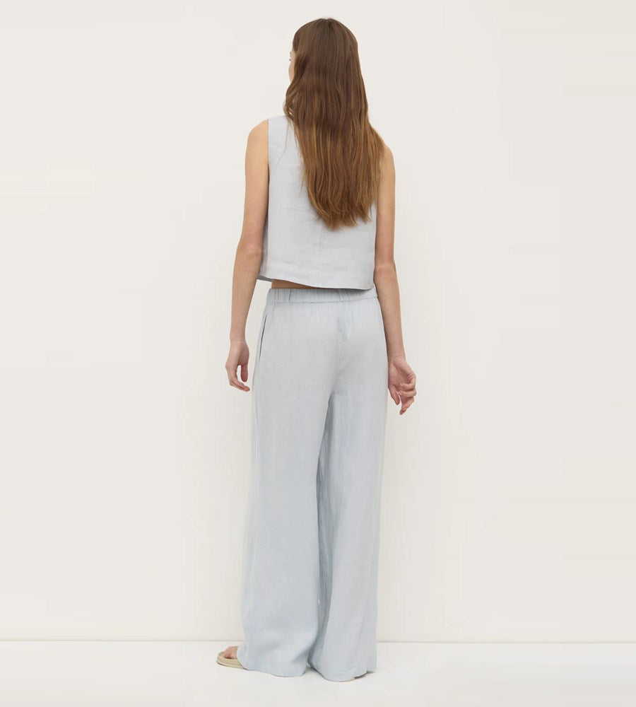 Woman wearing a light gray sleeveless top and wide-leg pants on a white background