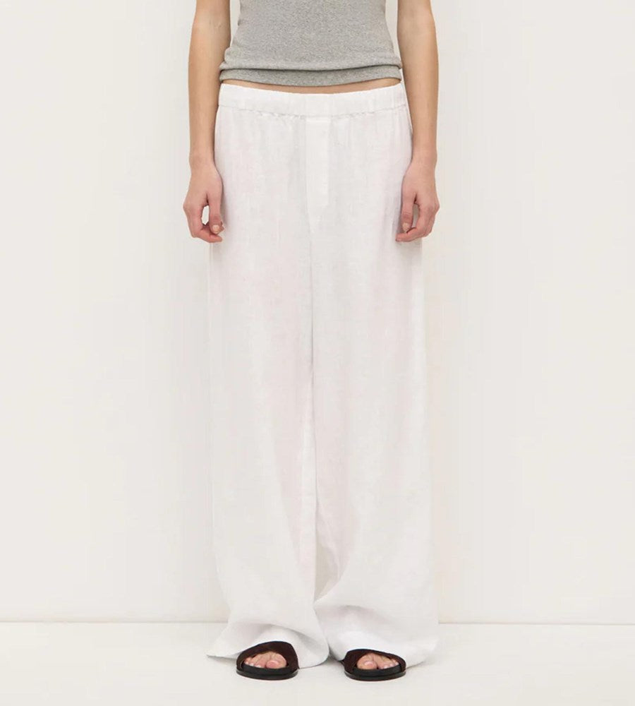Person wearing white pants and a gray top on a plain background