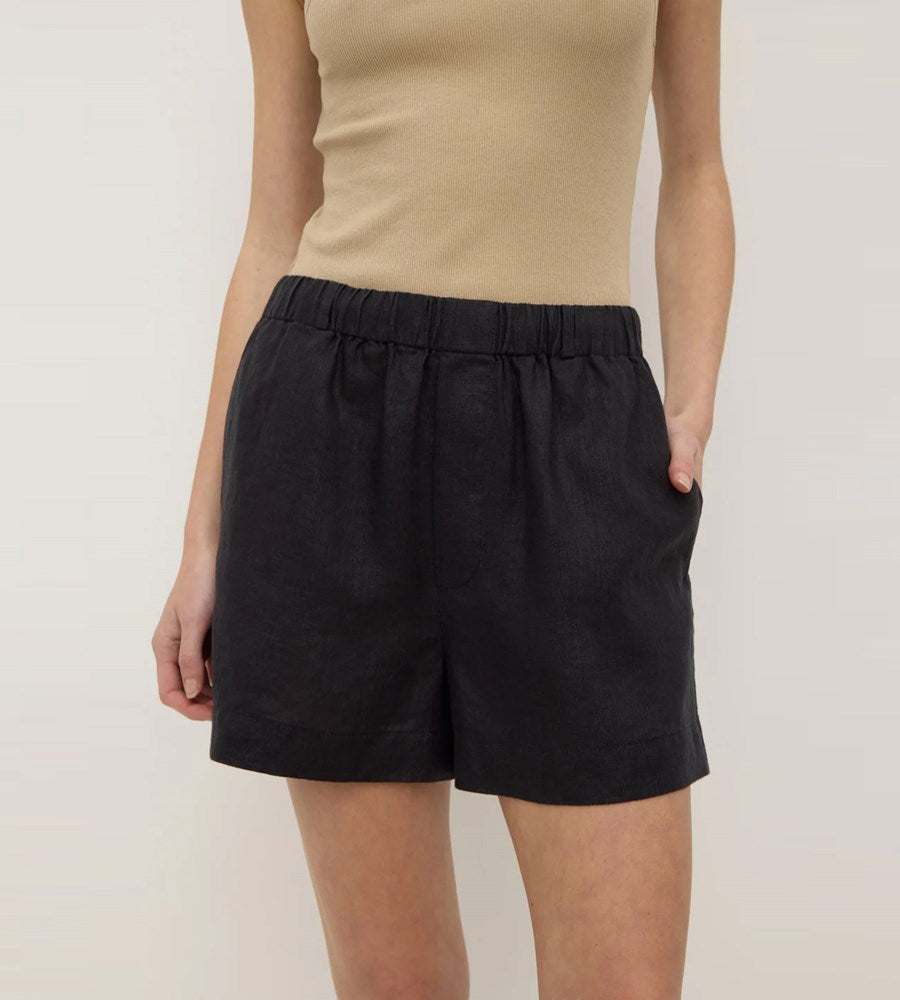 Person wearing black shorts and a beige top on a plain background