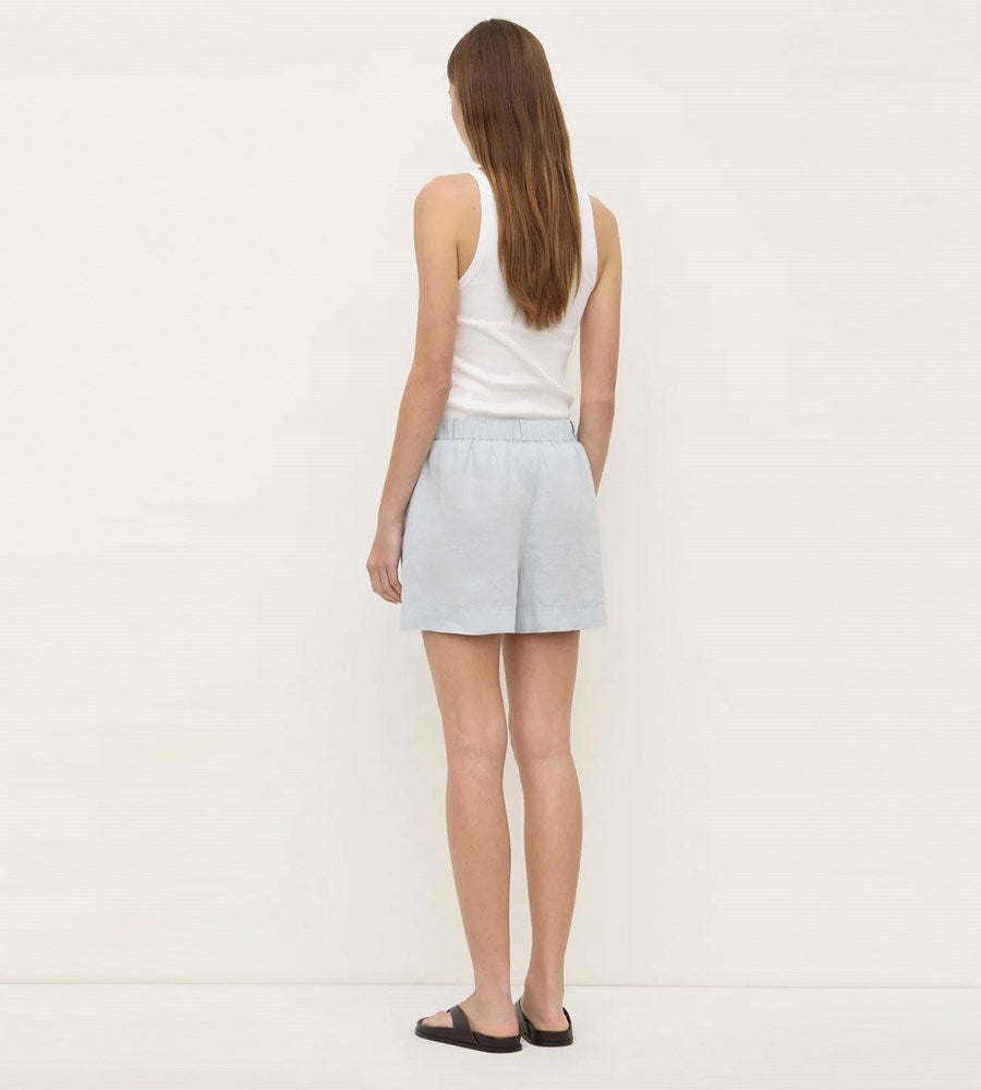 Woman wearing a light blue skirt and white top on a plain background