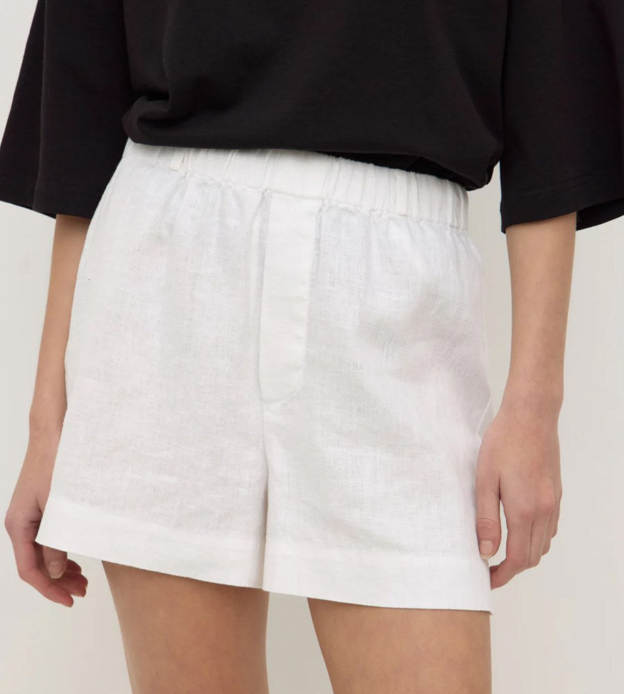 Person wearing white shorts and a black top on a plain background