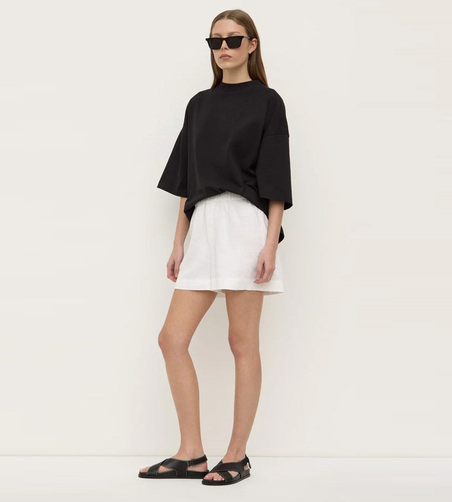 Woman wearing a black top and white skirt against a white background