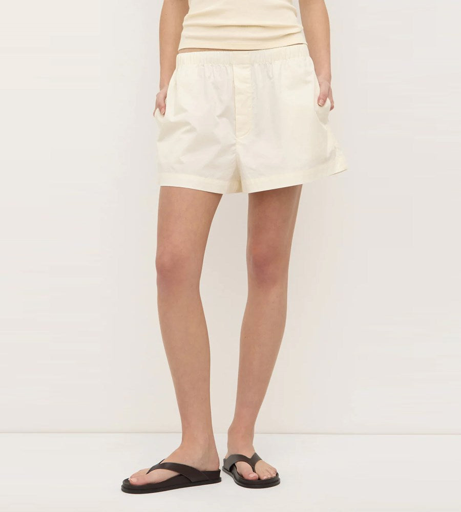 Person wearing cream shorts on a white background