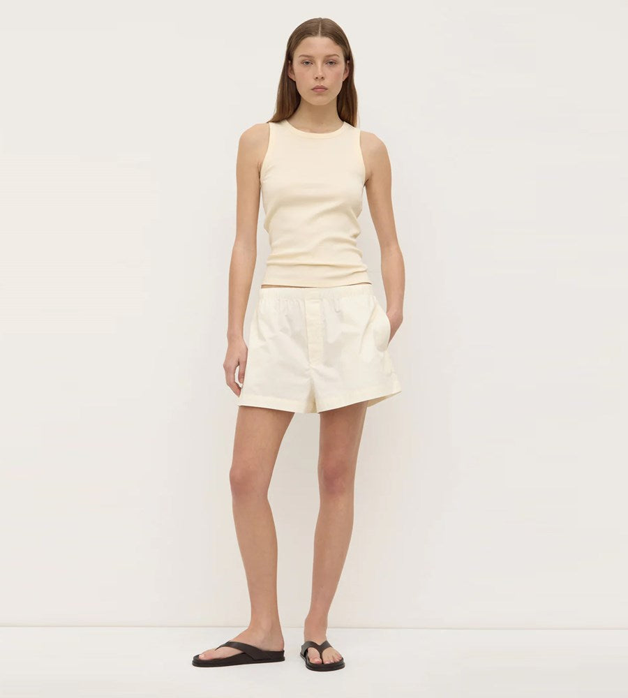 Woman wearing a cream-colored sleeveless top and shorts on a white background