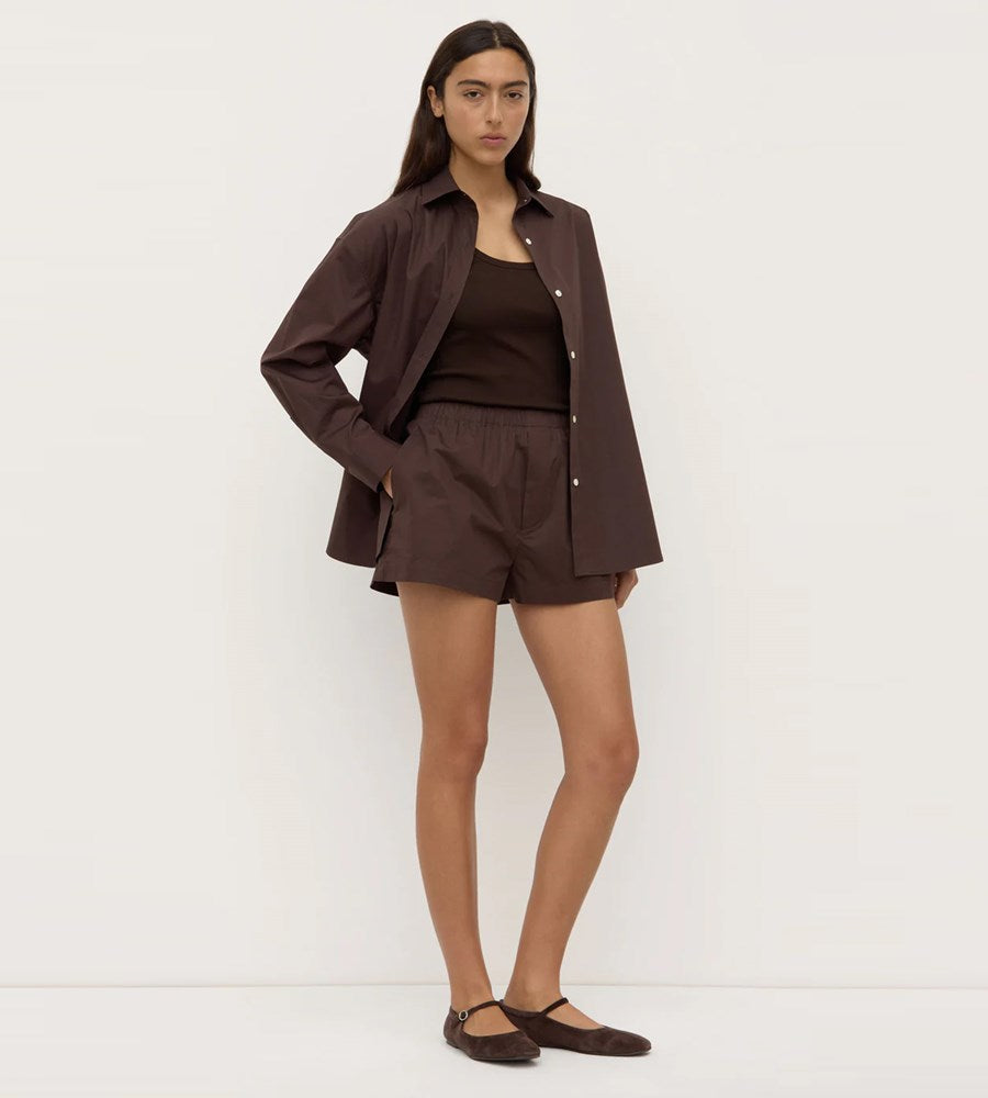 Woman wearing a brown outfit with a jacket and shorts on a white background