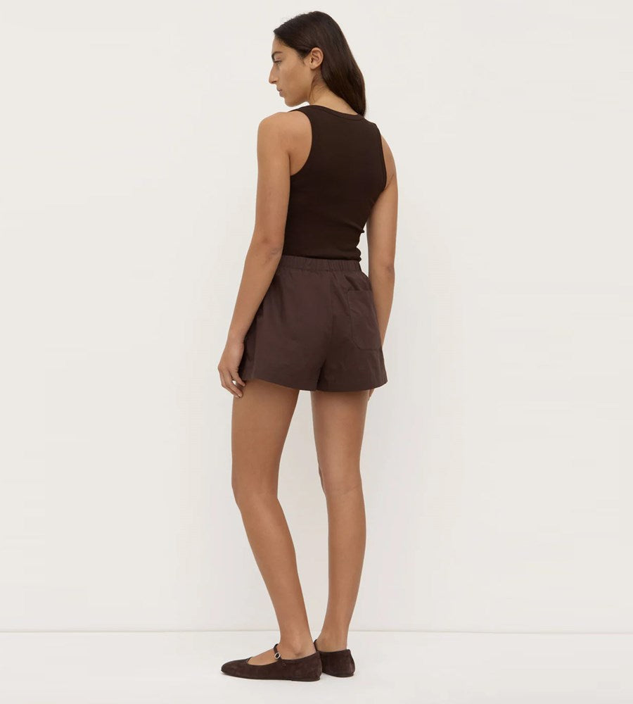 Woman wearing a brown sleeveless top and shorts on a white background
