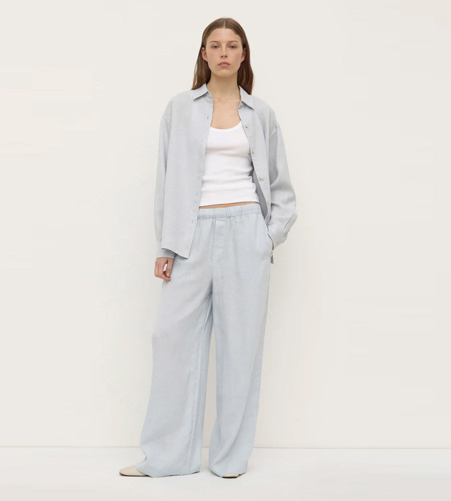 Woman wearing a light gray outfit with a white top on a plain background