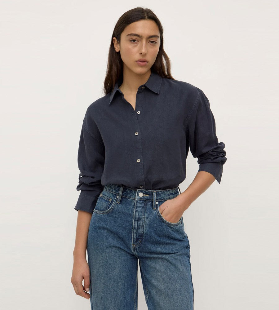 Person wearing a navy shirt and blue jeans on a plain background