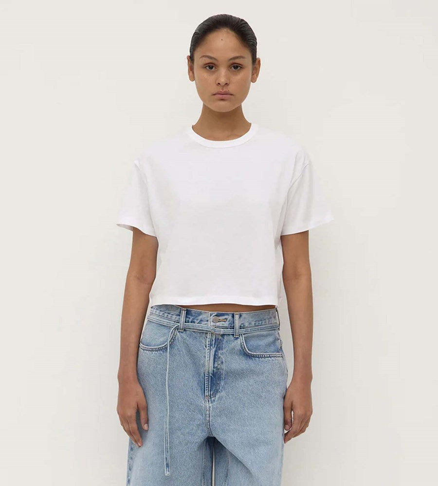 Person wearing a white t-shirt and blue jeans against a plain background