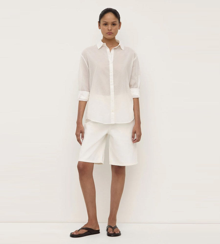 Person wearing a white shirt and shorts on a plain background