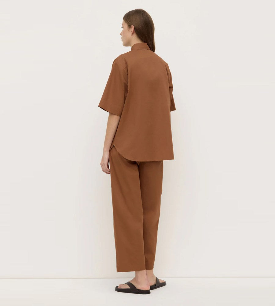 Person wearing a brown outfit standing against a white background