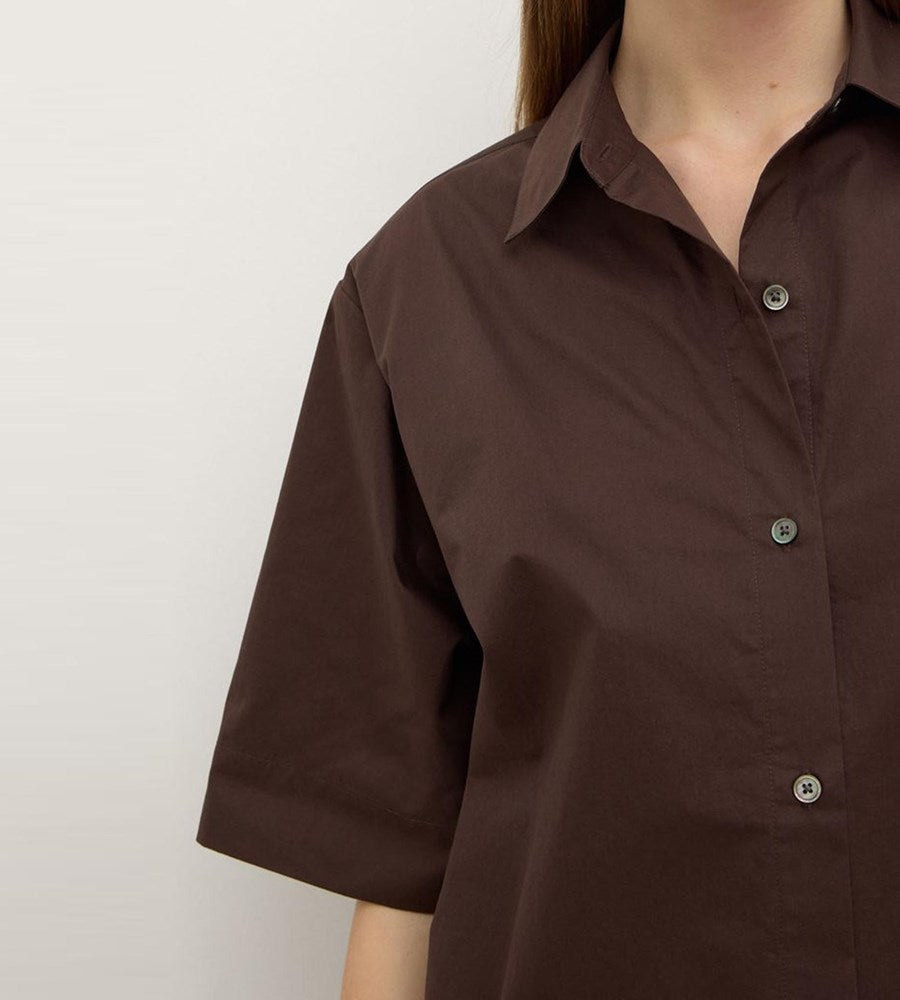 Brown short-sleeve shirt worn by a person on a plain background